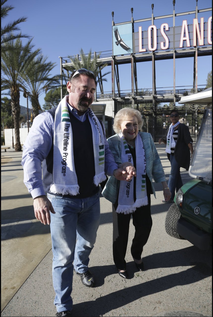 Stephen E. Terrell walking hand in hand with Betty White at the Los Angeles Zoo, both wearing Lifeline Program scarves
