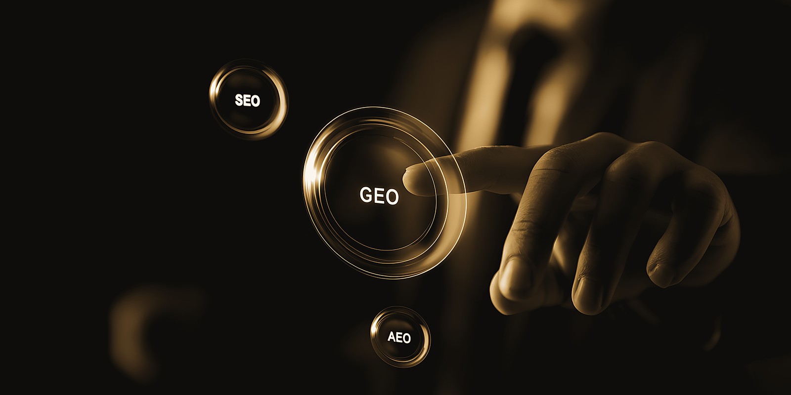 A hand pressing a glowing GEO button beside smaller SEO and AEO buttons, in black and gold